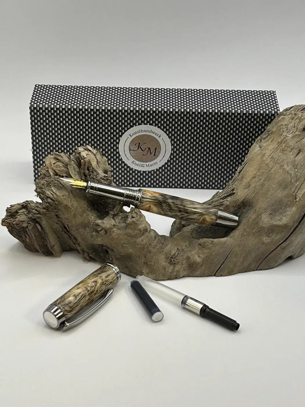 Füllfeder aus Zirbenholz auf einem Holzast liegend