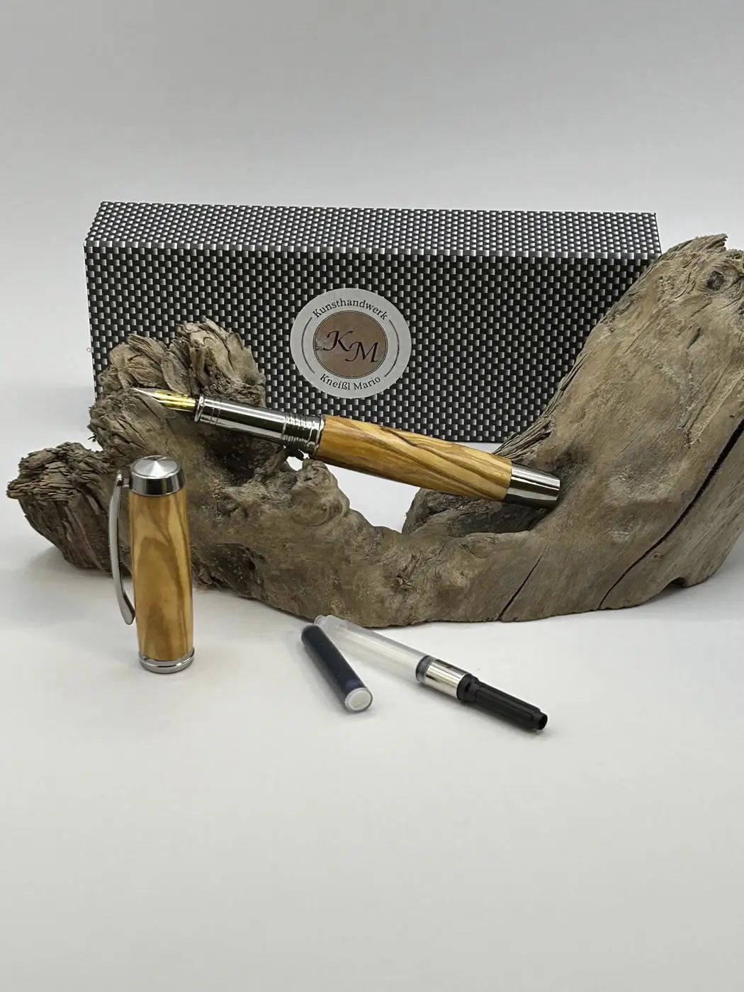 Füllfeder aus Olivenholz auf einem Holzast liegend